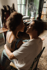 young interracial couple embracing and looking at each other in art studio.
