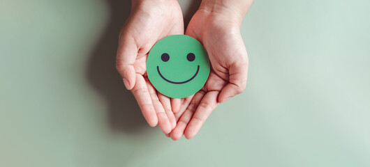 Hands holding green happy smile face, good feedback rating, positive customer review, experience,...
