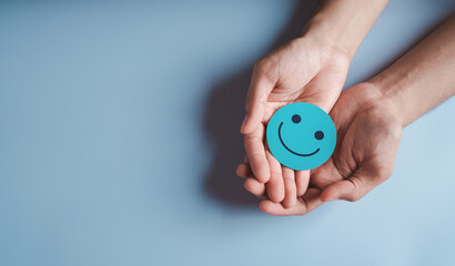Hands holding blue happy smile face, good feedback rating, positive customer review, experience,...
