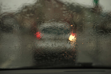 Turning car with turn signal on the right blurred photographed during dusk through a wet windshield