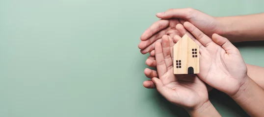 Foto op Canvas hands holding wooden house, family home, homeless housing, mortgage crisis and home protecting insurance, international day of families, foster home care, family day care, stay home concept © Kiattisak