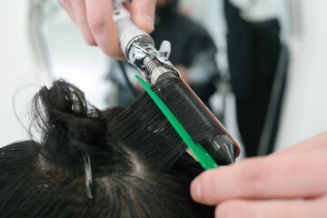 Naklejka premium Close-up of a man's hair perming with a hairdressing tool