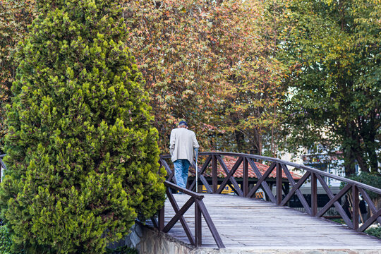 Autumn season, view of old uncle crossing the bridge in the park