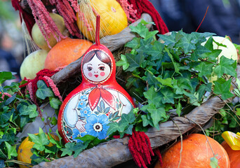 Russian wooden doll Matryoshka in composition with pumpkins.