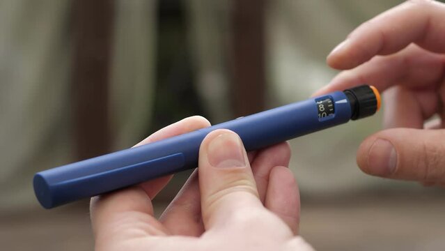 A diabetic man holding in hands a syringe pen with an insulin cartridge. A scale window on a syringe with a handle showing the number of dose units.Diabetes and prevention of diabetes complications