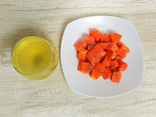 Healthy food, fresh papaya slices on a white plate and cup of juice with Chia seed topping on table