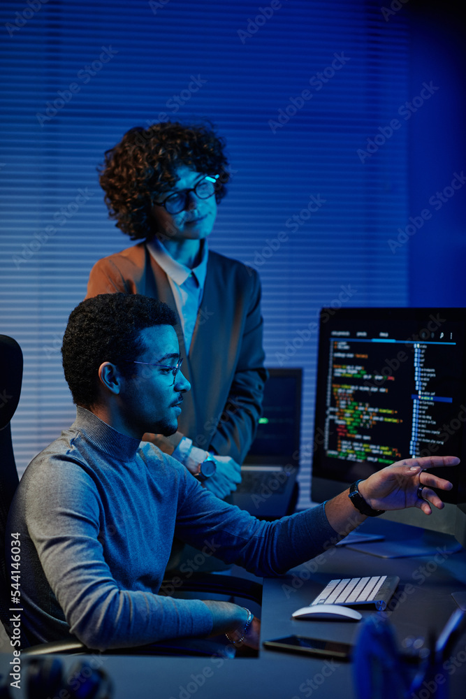 Poster Confident IT engineer or software developer pointing at codes on computer screen while making presentation to female colleague