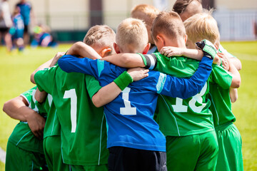 Happy boys play team sport. Kids smiling in school sports team. Children together in huddle....