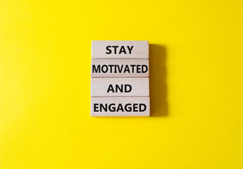 Stay Motivated and Engaged symbol. Concept words Stay Motivated and Engaged on wooden blocks. Beautiful yellow background. Business and Stay Motivated and Engaged concept. Copy space