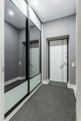 Entrance hall attached to small modern living room, doors to wardrobe opened.