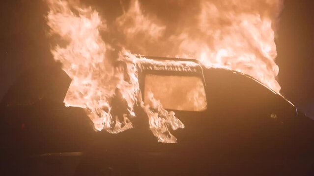 Burning car slow motion tilt movement. Automobile on fire vertical camera move.
