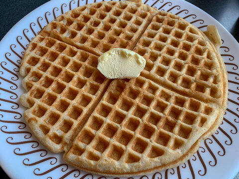 A golden brown waffle with butter.