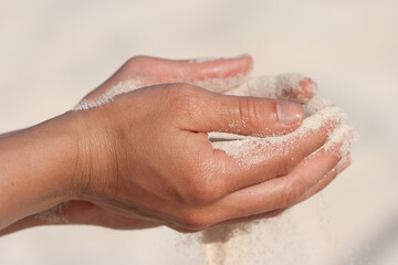 Fototapeta premium Sand running through hands on beach