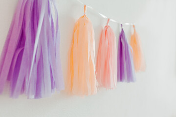 Tissue paper tassel garland. Pastel colors on the white background. Decoration for party. Minimalist style, copy space