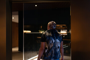 Non-binary person walking into a store for winter shopping, holding bags.