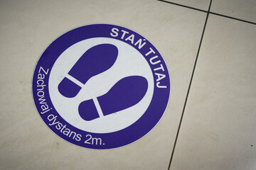 Aufkleber am Boden eines Einkaufszentrums in Polen mit den Worten: Stan Tutaj Zachowaj dystans 2m....