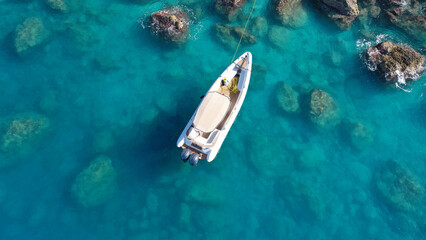 Aerial drone top down photo of white inflatable rib speed boat anchored in tropical exotic rocky...