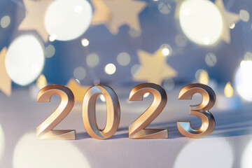 Golden numbers of year 2023. Glowing festive garland with bokeh on light background.