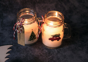 Lit Christmas candles of white paraffin in a glass, decorated with a car and a Christmas tree on a...
