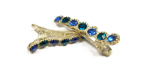 Hairdresser's gold clamps isolated on white back. Beauty gold hairpin with blue rhinestones...