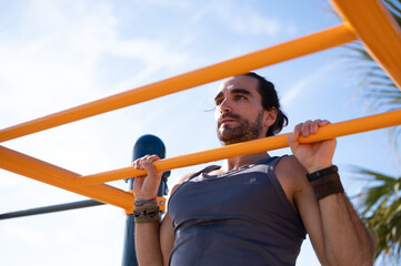 Adult man doing muscle up on a bar practicing calisthenics exercises. Sports concept.