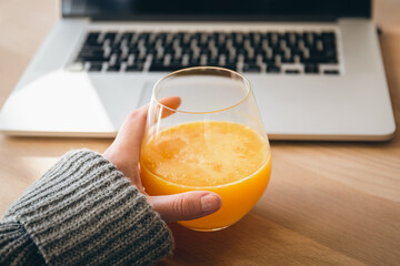 A glass of orange juice and a laptop, the concept of work and study.