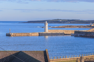 A scenic view of a Scottish port entrance from above with some house roof in the foreground and in...