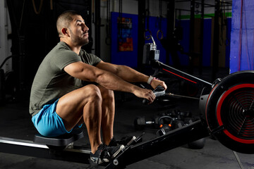 Fototapeta na wymiar man in sportswear rowing on a machine in a gym