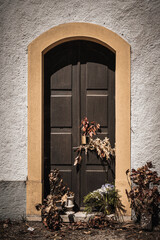 Different types of herbs are left at the entrance wooden door of a chapel by believers as offerings for performing religious rituals. Toned image in sepia colors