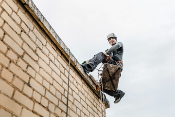 Male worker rope access industrial working at height tank oil wearing harness, helmet safety equipment rope