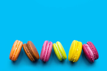 multicolored macaroons on colored background, French delicacy, top view