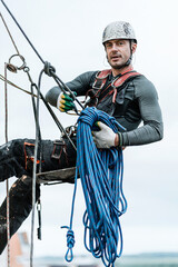 Male worker rope access industrial working at height tank oil wearing harness, helmet safety equipment rope