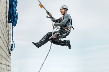 Male worker rope access industrial working at height tank oil wearing harness, helmet safety...
