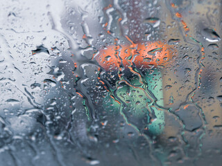 Wet window glass with raindrops, water drippings and blurred colors  
