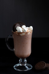 Viennese Coffee In Glass Cup With Whipped Cream. Hot chocolate with marshmallow and cookie. Winter and autumn time. Christmas drink on the black background. copy space