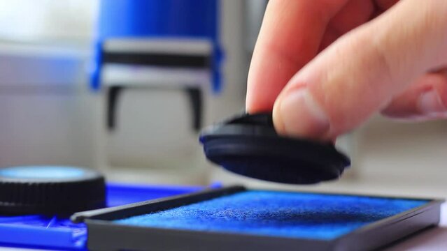 Male hand wets a stamp in ink closeup