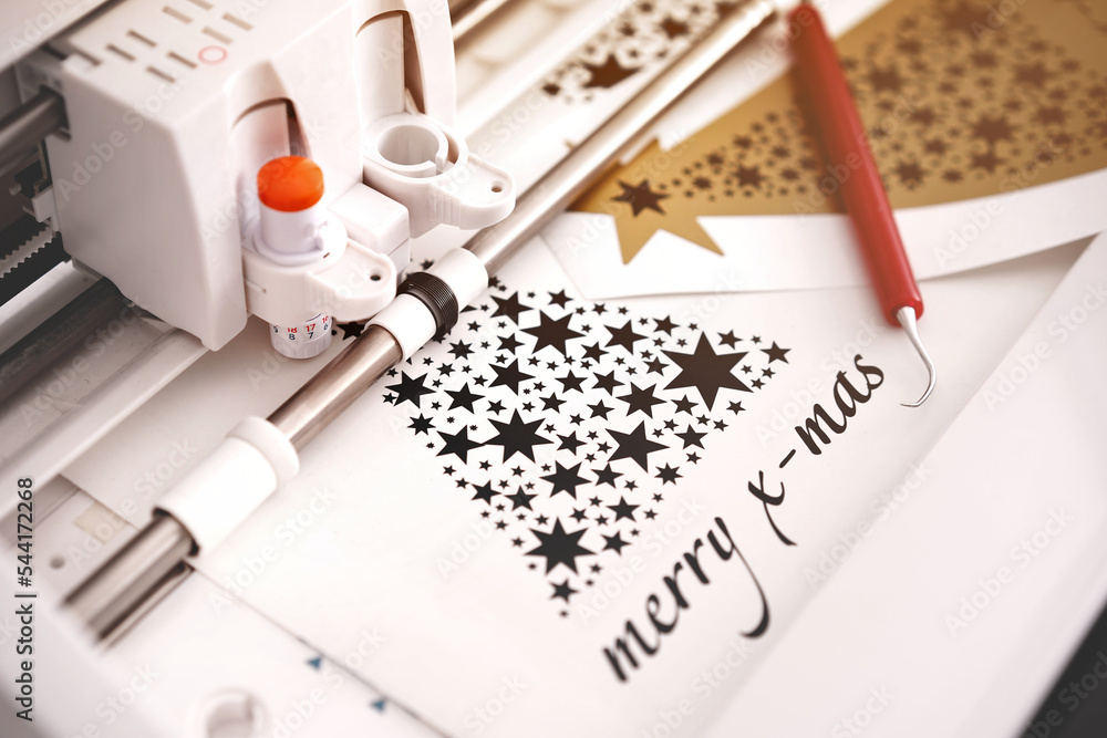 Fototapete machine head of plotting machine with adjustable blade cuts christmas sticker with lettering from bl
