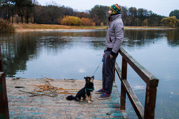 Obraz na płótnie Canvas Bearded man with his dog playing in autumn park near lake.