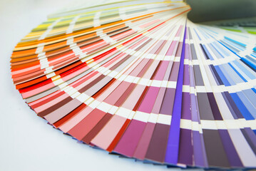Color guide close up. Assortment of colors for design. Colors palette fan on white concrete wall background. Graphic designer chooses colors from the color palette guide.