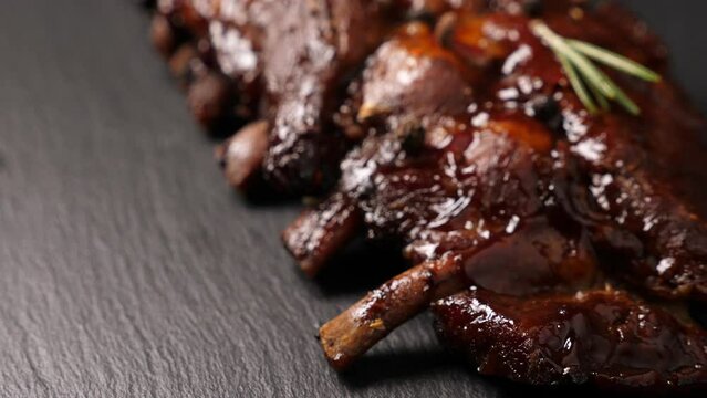 Grilled pork ribs served on black slate plate. Closeup