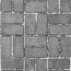 Naklejka premium Gray paving slabs with seams powdered with snow. Early winter.