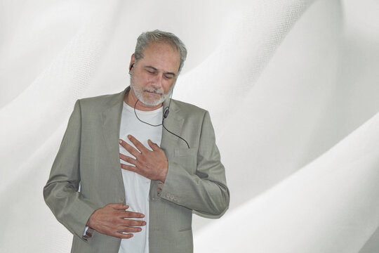 Mature Man With Headphones In Suit Dancing On A White Background