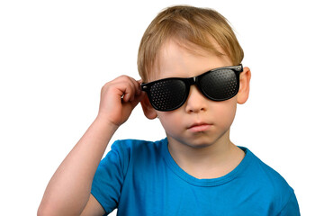 A little boy in black medical glasses for vision correction on a white background. Holds glasses with his right hand