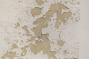 Peeling paint on gray concrete wall. Peeling, cracking, or blistering paint occurs when there is a loss of adhesion between the paint and the surface it's placed on.