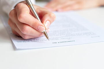 Close shot of a woman hand writing something on the paper on the foreground