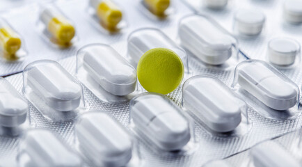 Pile of medical pills in white and yellow colors. Tablets in plastic packaging. The concept of...