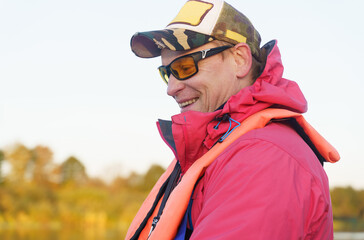 Portrait of a fisherman in sunglasses, cap, safety vest.