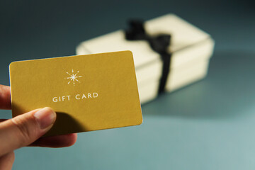 Hand holding a yellow gift card against a gift box background