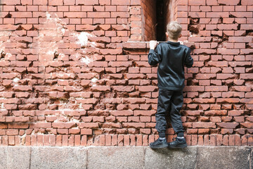 Fototapeta na wymiar A little boy walks near the old fortress