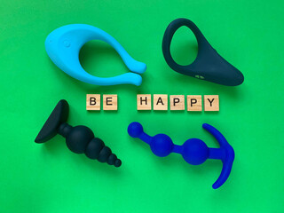 Sex toys. Vibrator, butt plugs and cock ring on green background. Inscription BE HAPPY. Useful for adult, sex shop © Olga Goretz